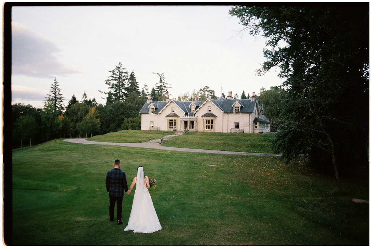 Bride and groom with their venue photographed on analogue film