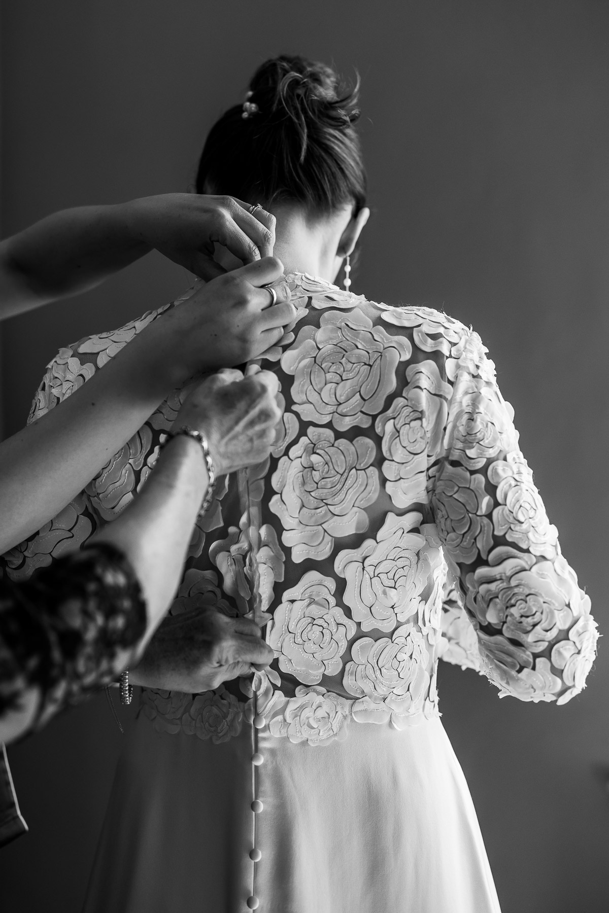 The bride having her gown buttoned up in the smoking room of Elmore Court 