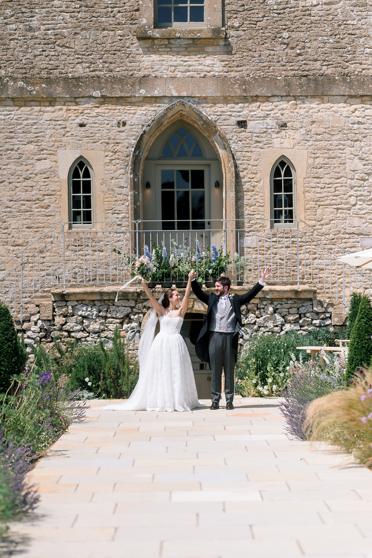 Couple with thie arms in the air outside Ivy lodge after the ceremony 
