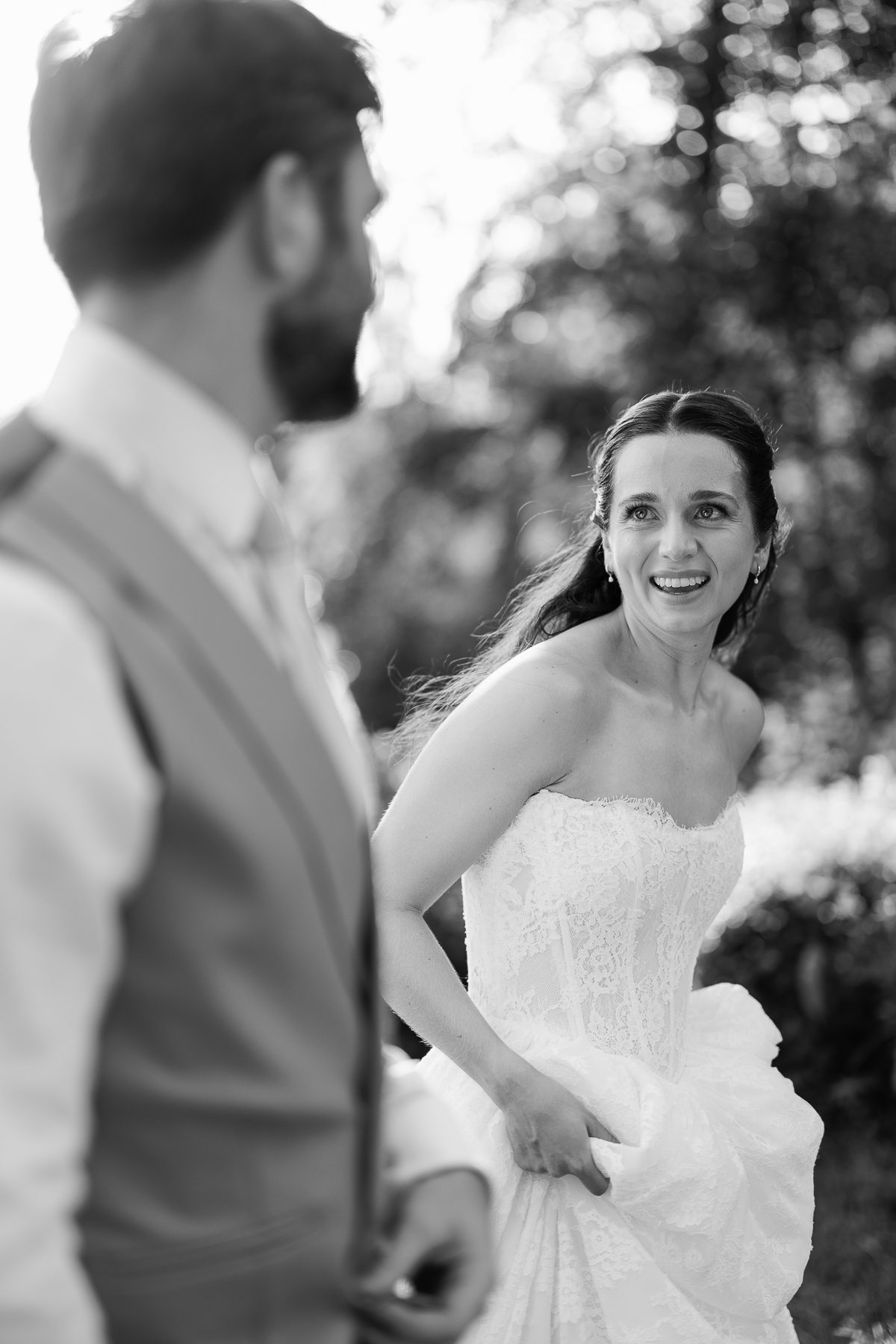 Bride walking pas the camera smiling at her husband 