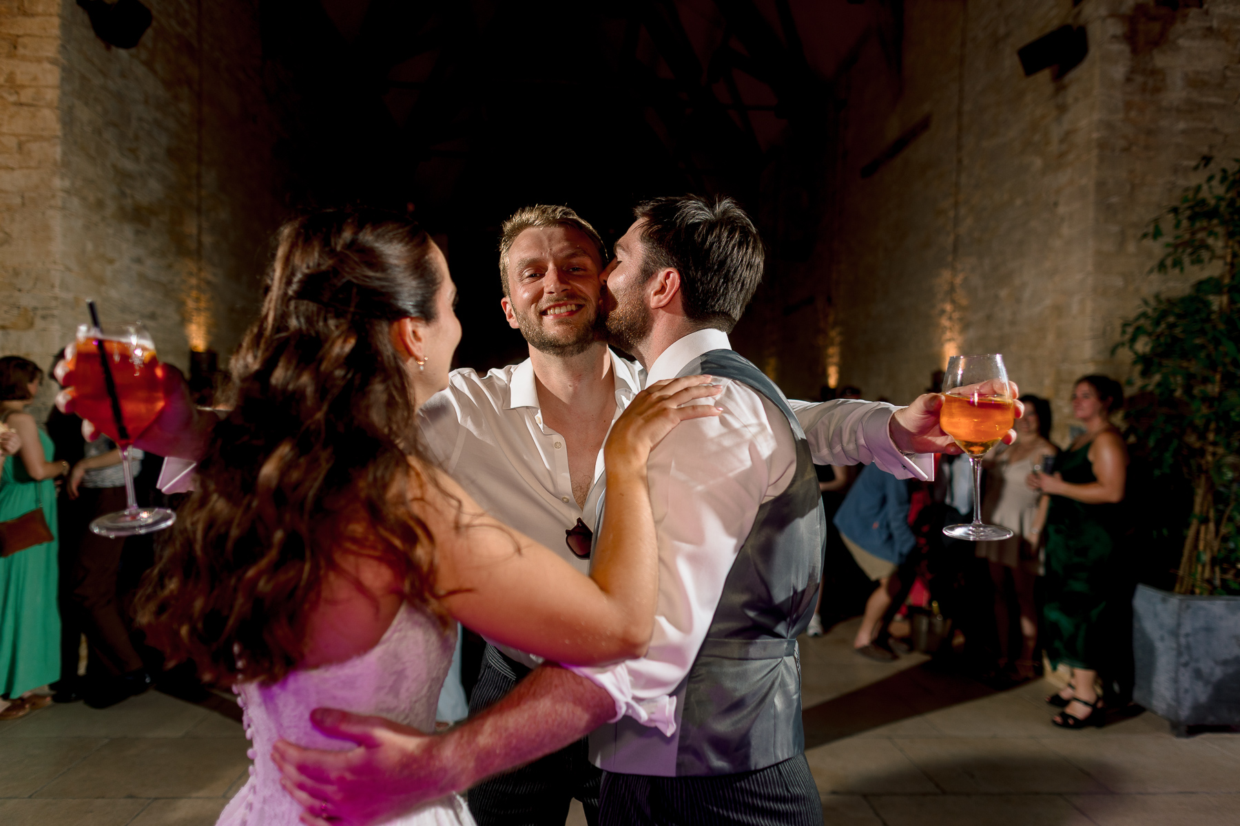 Best man hugging couple on the dancefloor