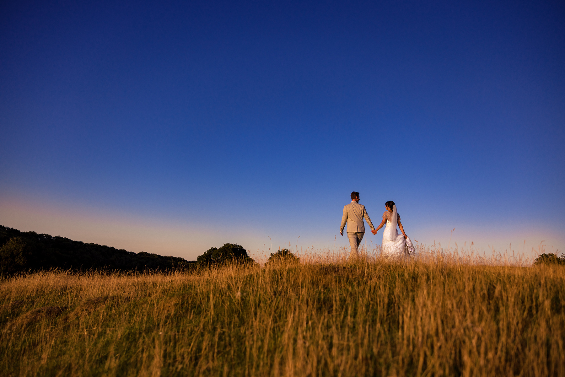 Bride and Groom walking over the hills at Kingscote Barn 
