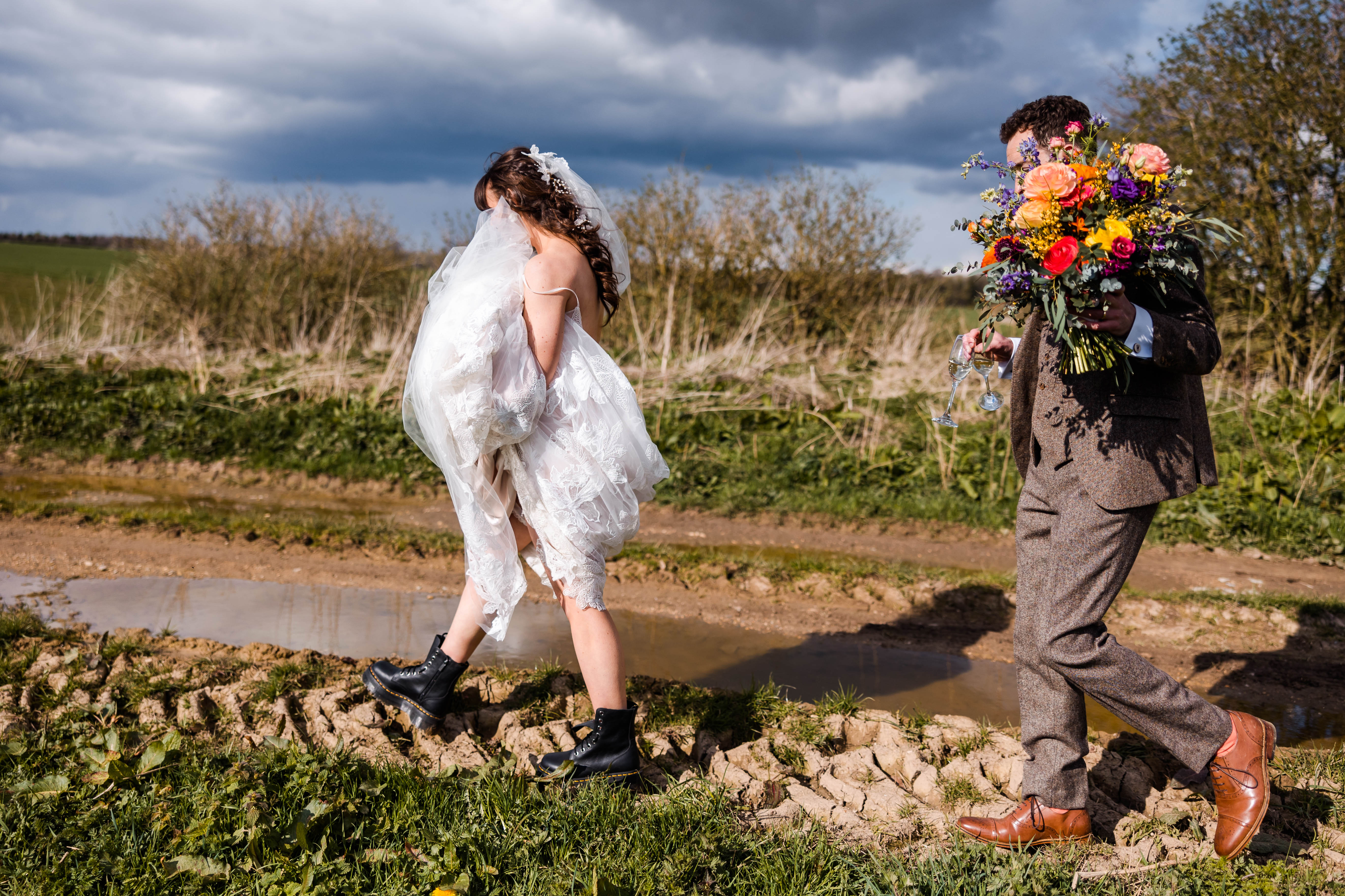 Couple walking through the mud at their Stone Barn wedding