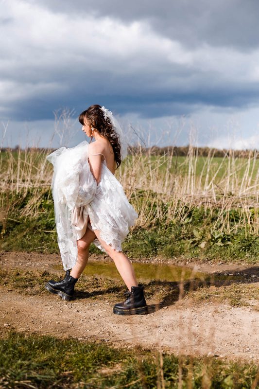 cotswold-wedding-photography-contact Bride walking through mud in her Dr Martins