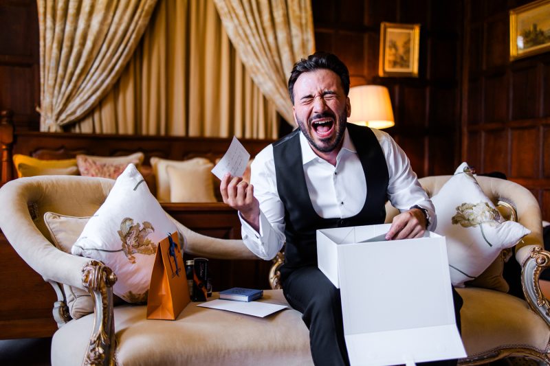 edp-55 Groom laughing at a letter in the bedroom at Elmore Court